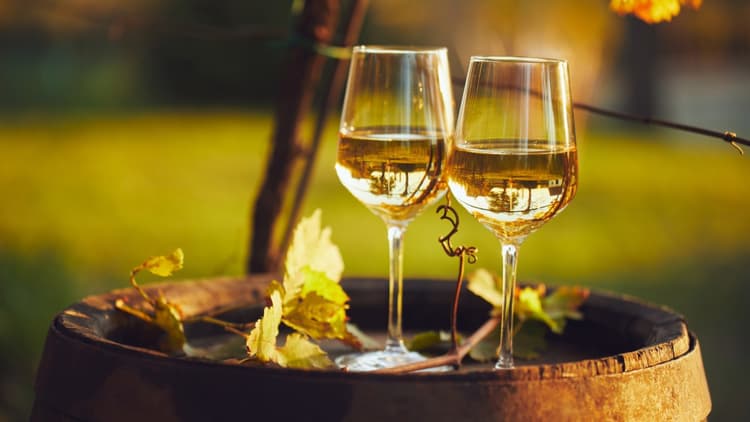 two glasses of white wine on a barrell to illustrate an article about how white wine changes as it ages